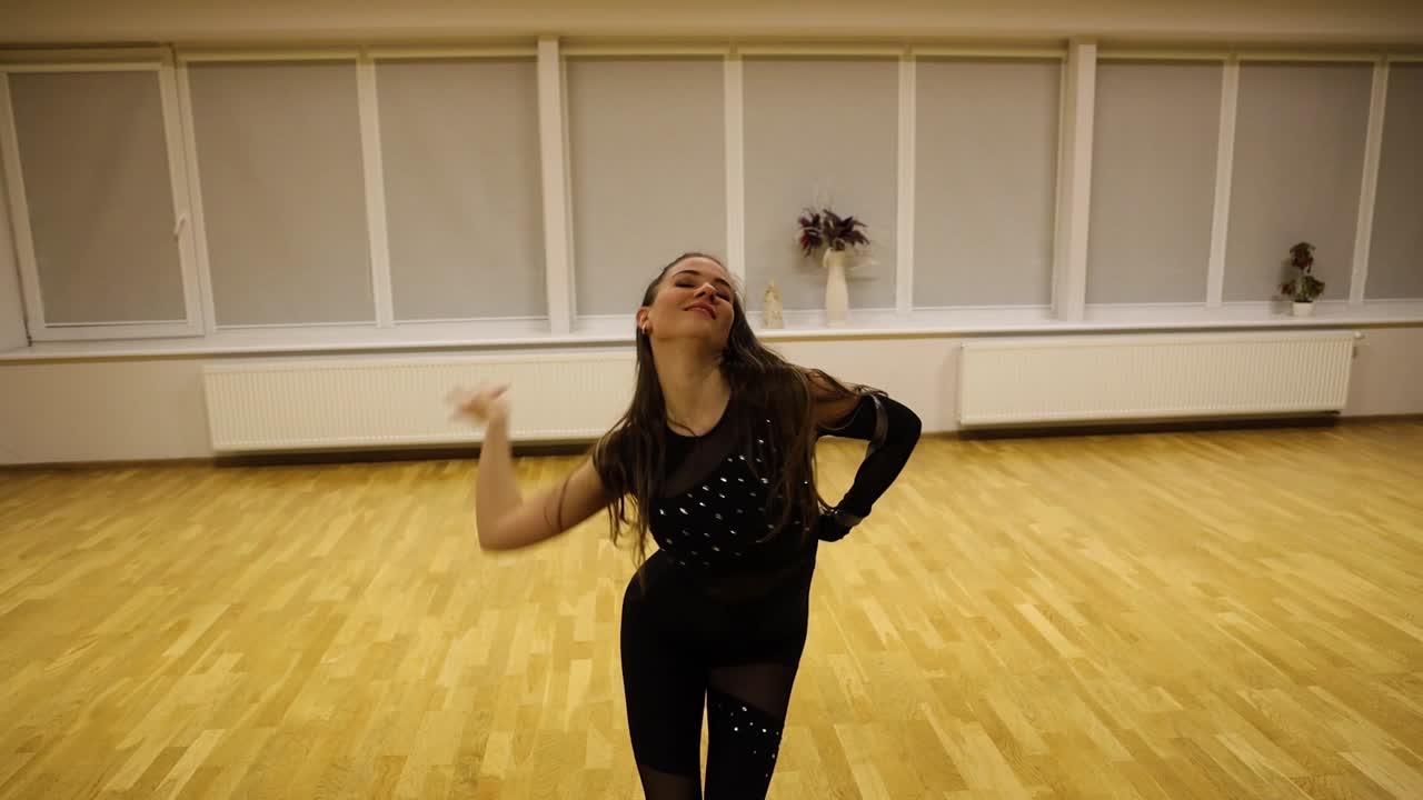 Professional young female dancer moving effusively while practicing a choreography