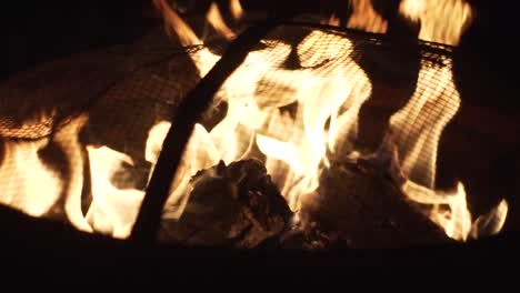 close up of flames and burning logs in a small fire pit on a cool summers night