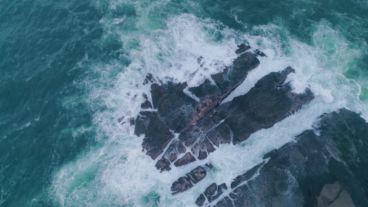 las olas del mar golpeando las rocas en cámara lenta capturan una vista aérea