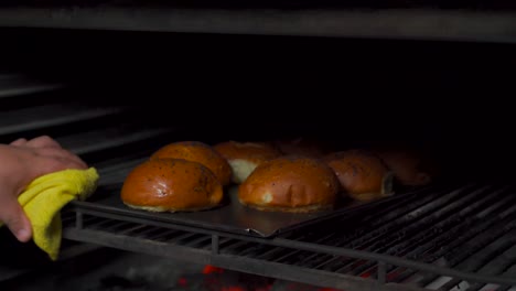 Baker-chef-cooker-take-out-fresh-hamburger-buns-of-charcoal-fire-grill-oven-brioche-bun-with-black-sesame-seeds