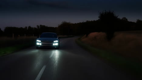 car driving on a dark road at night with headlights on