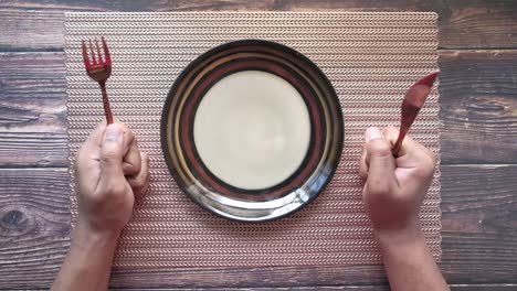 cutlery and empty plate on wooden background top down