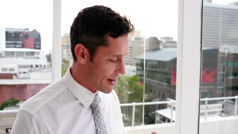 Handsome-businessman-drinking-coffee-and-looking-out-window