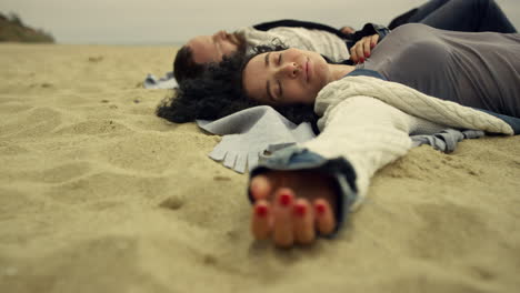 una pareja hispana relajándose en la arena de la playa junto al mar, amantes relajados acostados a la orilla del mar.