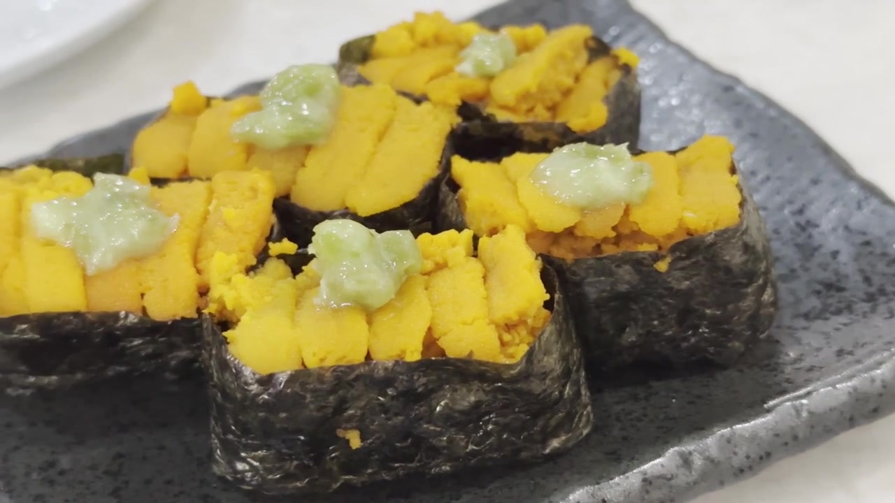 Primo piano di sushi uni fresco con riccio di mare di alta qualità servito su riso giapponese condito, che evidenzia una consistenza ricca e una presentazione gourmet autentica