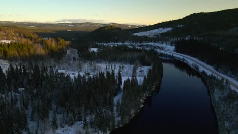 flying over curved river in winter landscape with vast forest, aerial