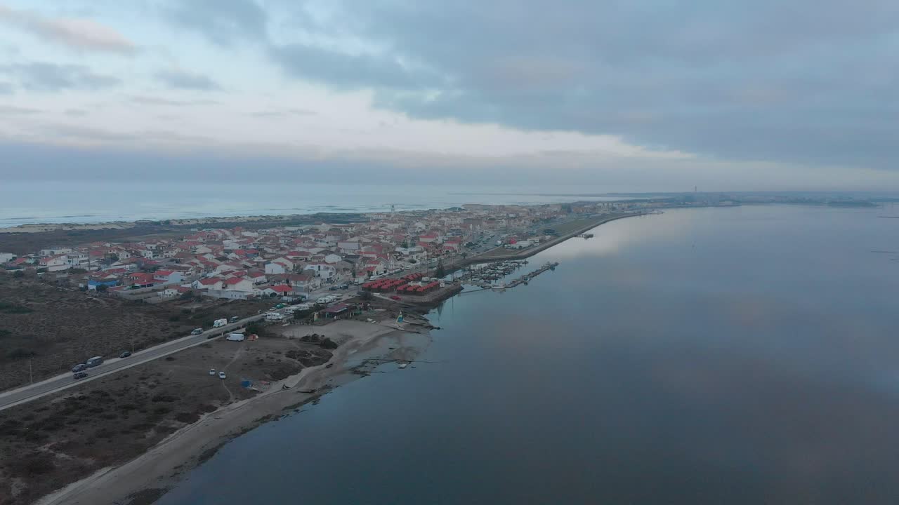 vista aérea de un pequeño pueblo entre el océano y el río en un día nublado