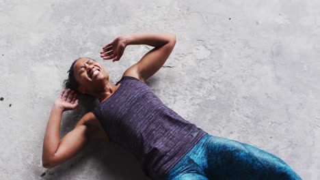 African-american-woman-doing-crunches-on-the-floor-in-an-empty-urban-building