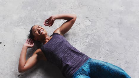 mujer afroamericana haciendo abdominales en el suelo en un edificio urbano vacío