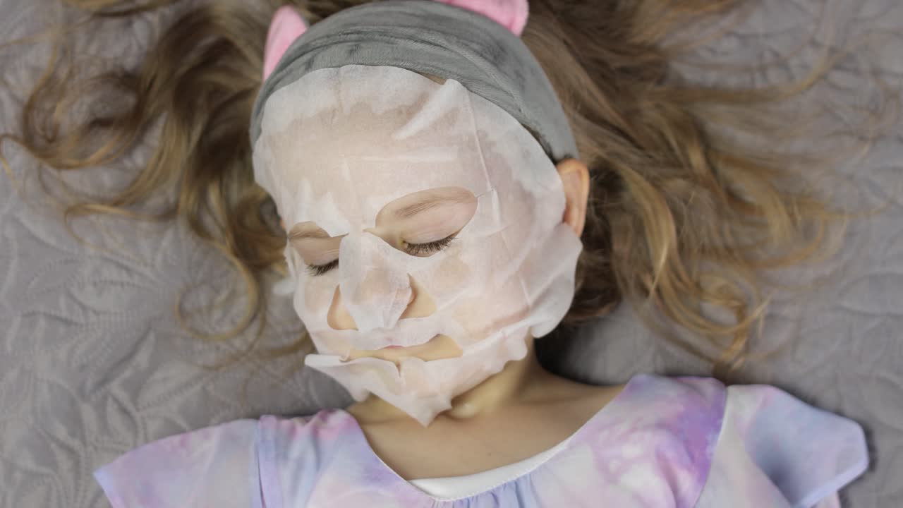 niña adolescente aplicando una máscara facial hidratante. niño niño cuida la piel con una máscaras faciales cosméticas