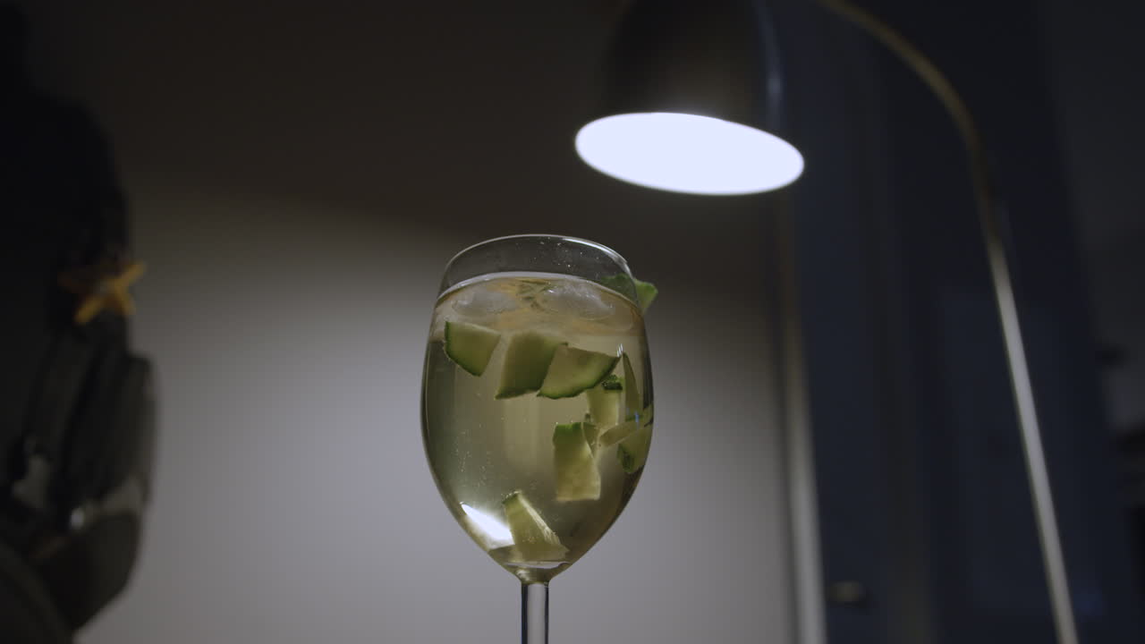 primer plano de ángulo bajo de una persona que deja un vaso de sangría, iluminación tenue y melancólica