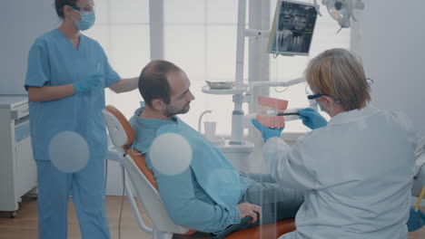 dentist giving hygiene lesson to patient to clean teeth correctly