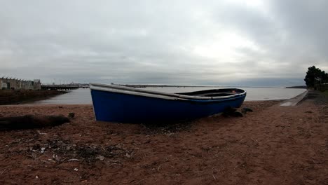 neglected blue rowing boat timelapse cloudscape on sandy dawn beach shoreline