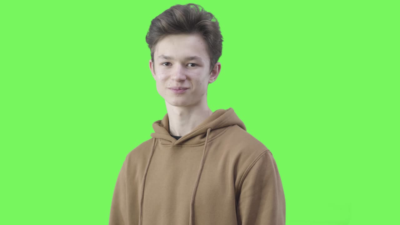 un niño caucásico alegre apuntando a la cámara con ambas manos y sonriendo. retrato de una adolescente morena con ojos marrones posando en un fondo cromakey. estilo de vida, emociones, ocio, alegría.