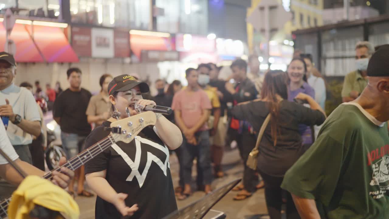 Local band buskers singing with band on Kuala Lumpur streets at weekend in Malaysia.