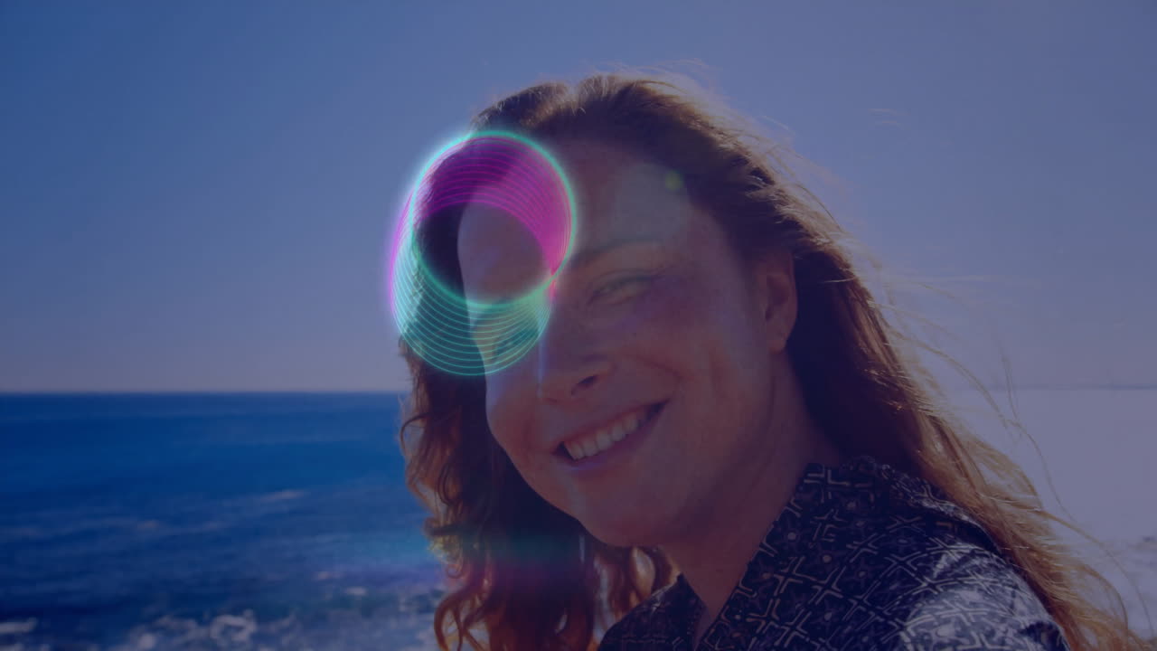 Person smiling by ocean with colorful circular animation overlay on face