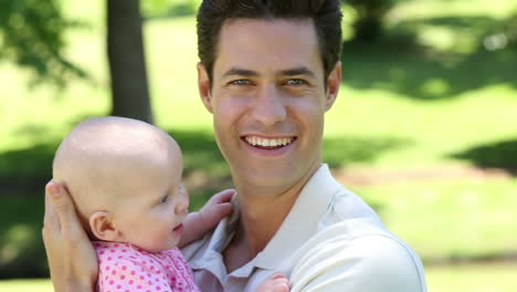 Happy-father-holding-his-baby-girl-in-the-park