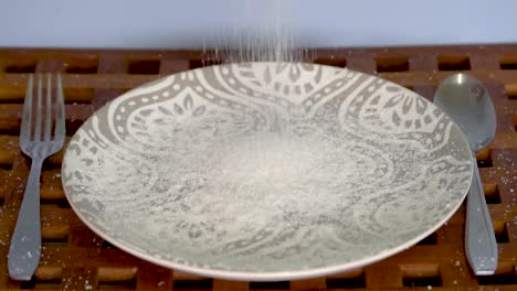 slow motion sugar falls on empty plate