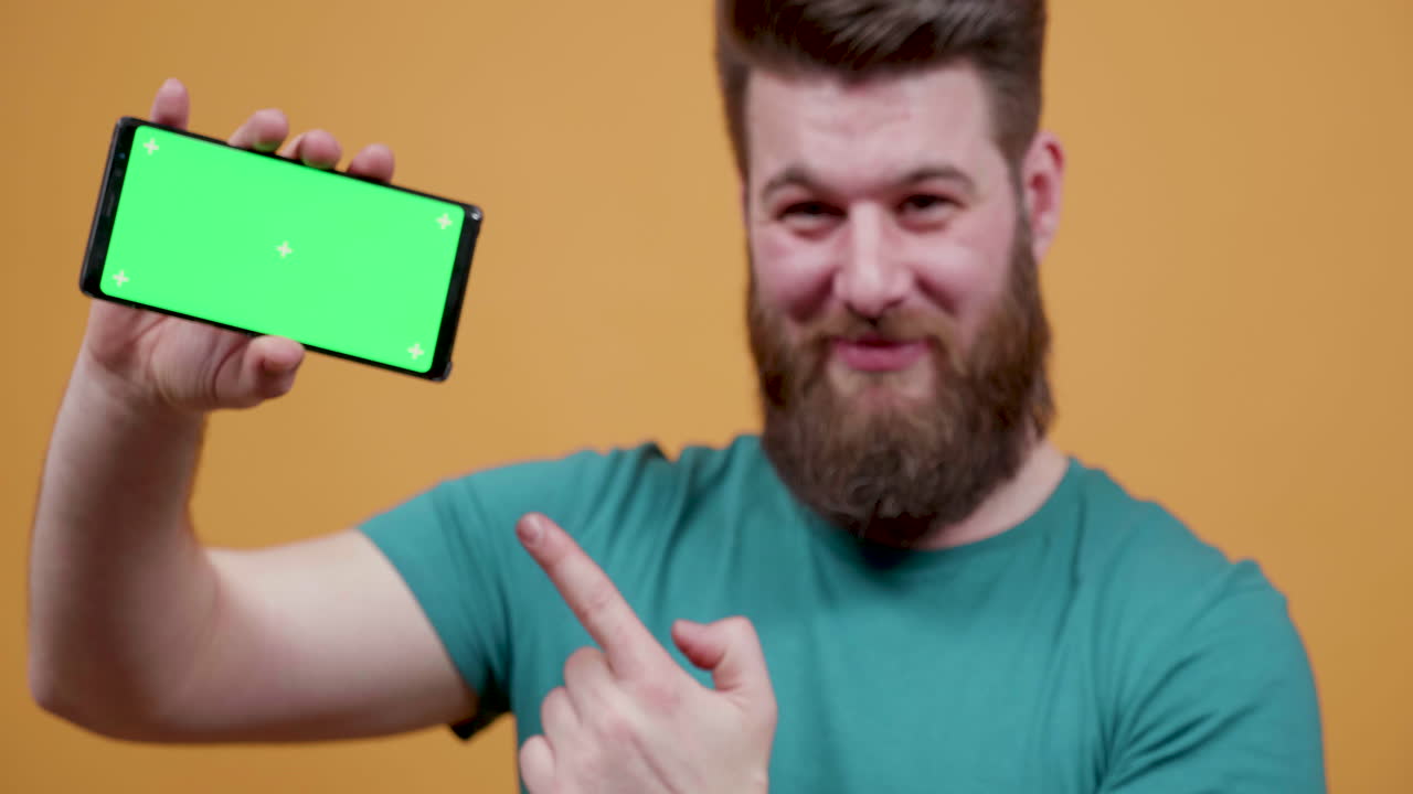 초록색 화면 을 가진 스마트폰 을 들고 있는 남자