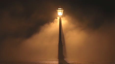 a lone street lamp illuminating dense fog at night