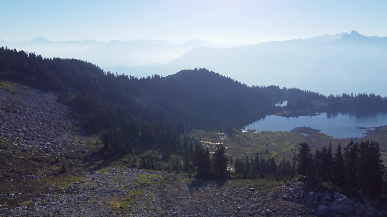Elegante ripresa aerea con drone di un lago di montagna e un paesaggio nebbioso sullo sfondo sul Monte Brew, Canada, 4K
