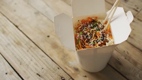 composition of box of pad thai with chopsticks on wooden background