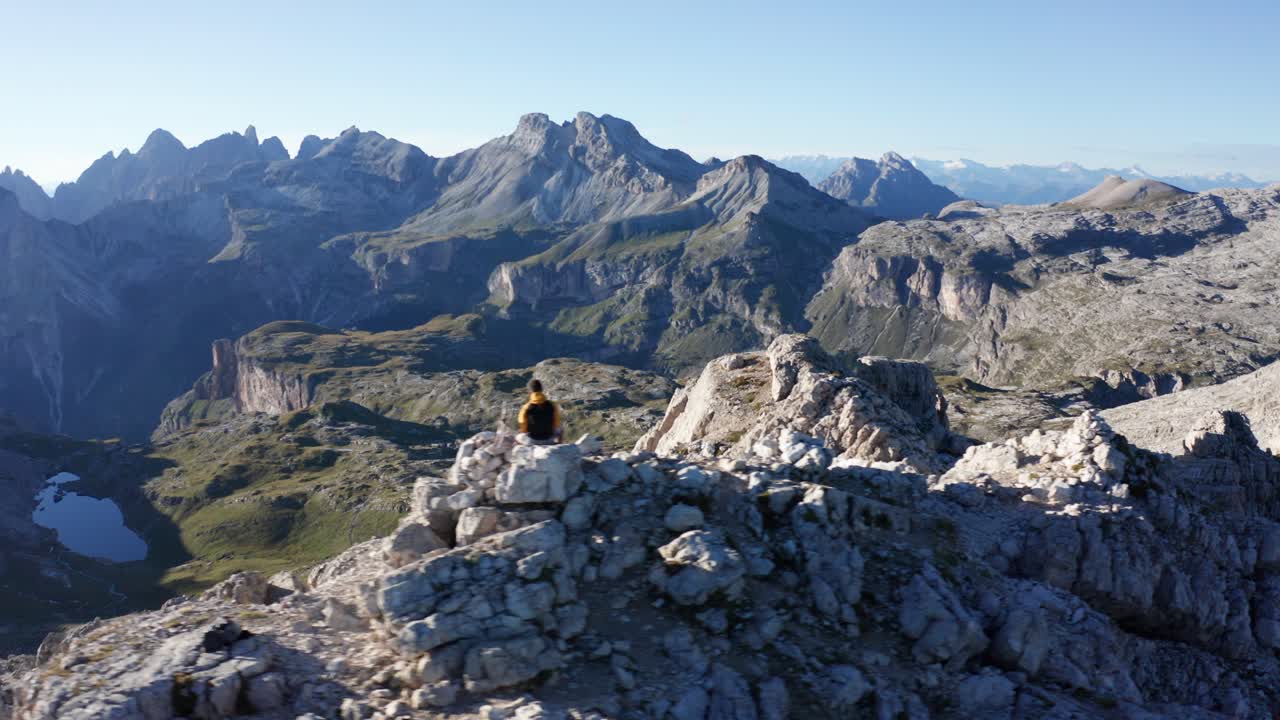 escalador de montaña sentado en la cima de la montaña, paisaje aéreo de dolomitas