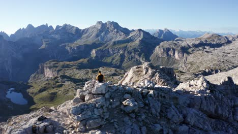 Escalador-De-Montaña-Sentado-En-La-Cima-De-La-Montaña,-Paisaje-Aéreo-De-Dolomitas