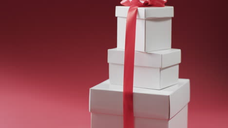 video of stack of presents with red ribbon with copy space on red background