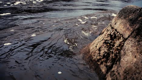 Ein-Steiler-Dunkler-Fluss-Mit-Einem-Felsen