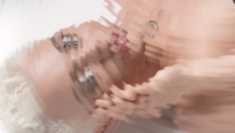 water portrait of blonde woman strokes face looking at camera