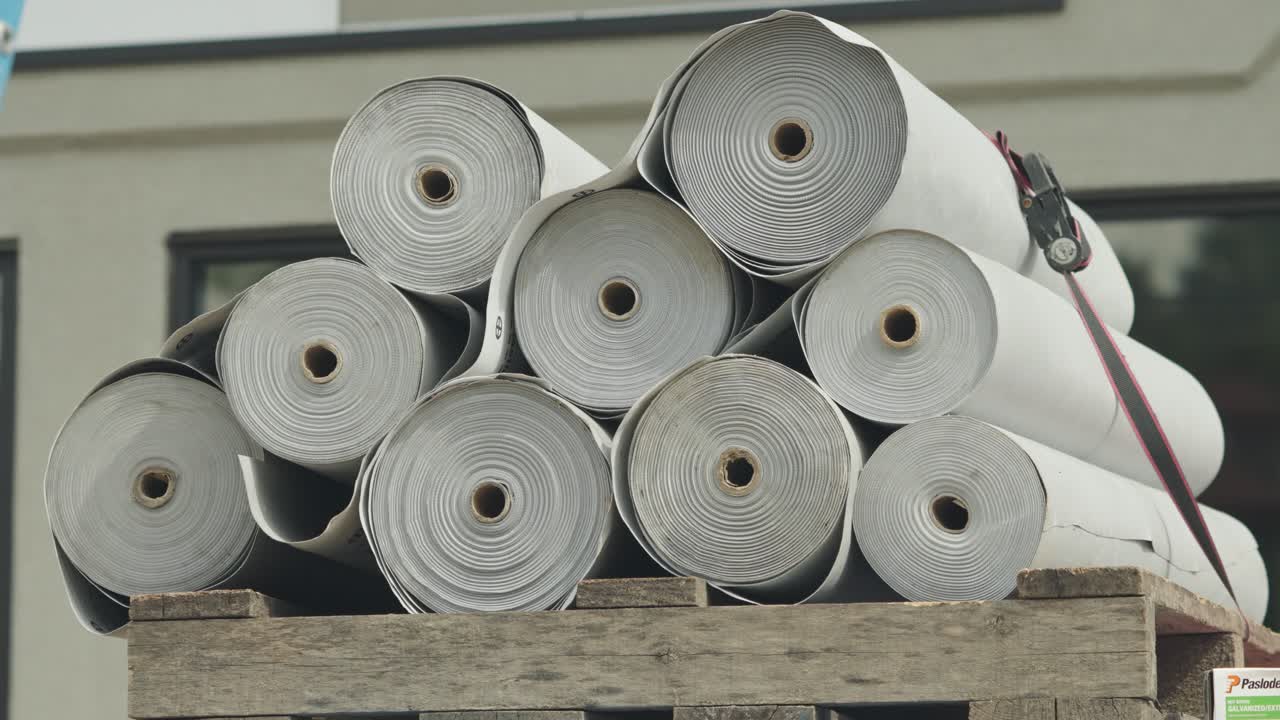 건설 현장에서 목조 팔레트에 끔하게 쌓인 여러 개의 지붕 하층 롤.