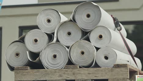 varios rollos de capa inferior de techo cuidadosamente apilados en una paleta de madera en un sitio de construcción.