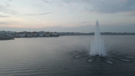 footage of the beautiful fountain standing in the middle of the water in the naval city of karlskrona, sweden on a cloudy day when the sun is about to set