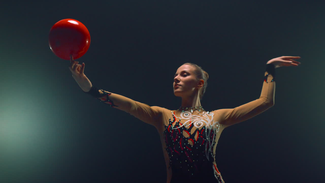 mujer deportista girando la pelota en el dedo en el interior. mujer gimnasta haciendo calistenia