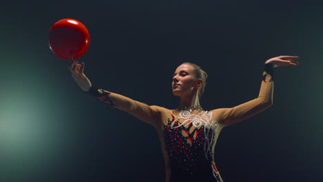 sportswoman spinning ball on finger indoors. woman gymnast doing calisthenics