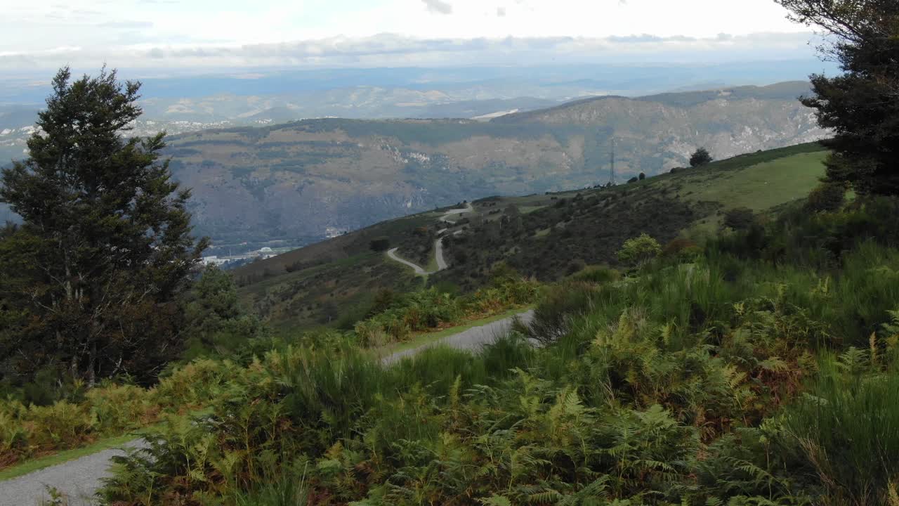 drone volando bajo sobre campos verdes con valle en el fondo, pirineos en francia