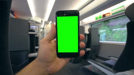 mano sosteniendo un teléfono con una pantalla verde en el tren