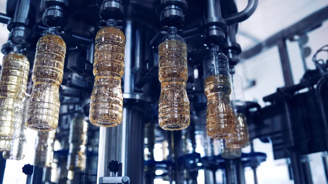 Roboterausrüstung in der Speiseölfabrik. Moderne Industrieanlagen füllen Sonnenblumenöl in Flaschen, die sich auf einer kreisförmigen Produktionslinie bewegen.