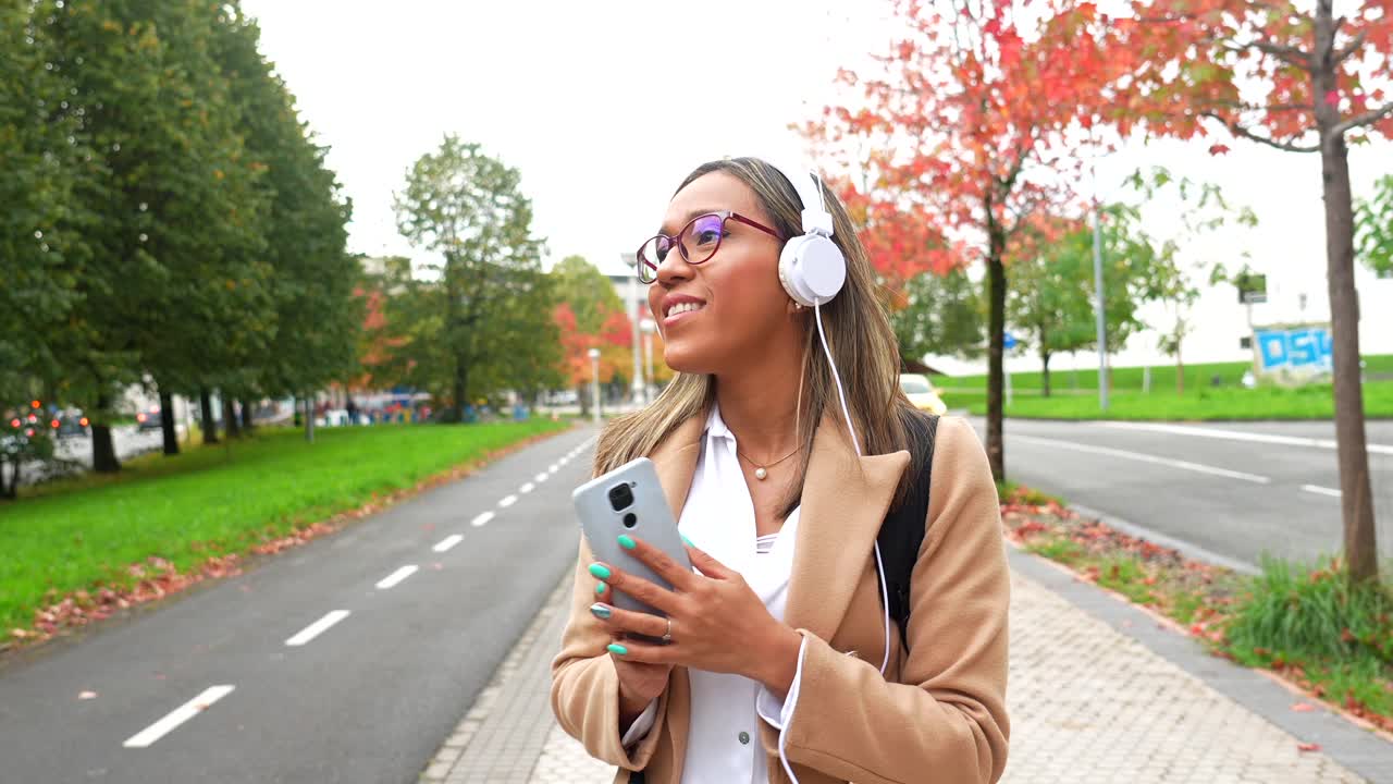 Woman with Headphones Walking on Street in Autumn