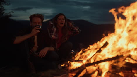 una pareja de familia en una cálida hoguera en el campamento nocturno. jóvenes amantes acurrucados al aire libre.