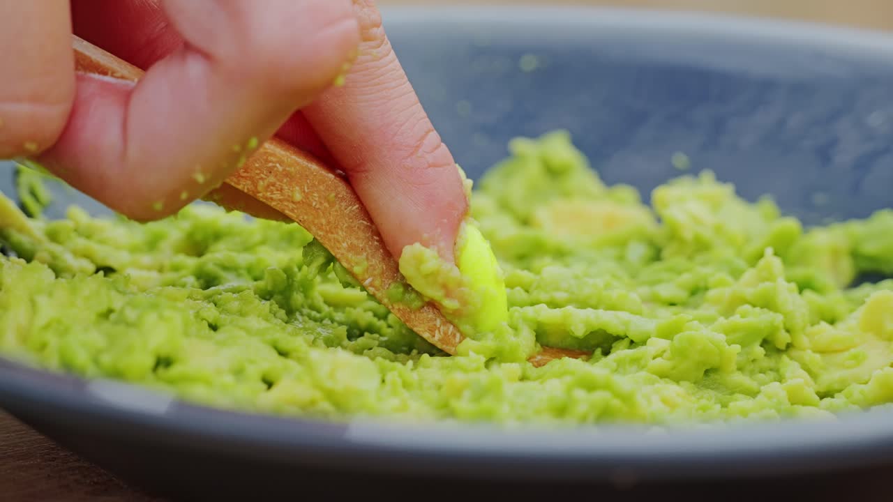 Momento eco-estetico mentre l'avocado cremoso viene schiacciato con un cucchiaio di legno naturale