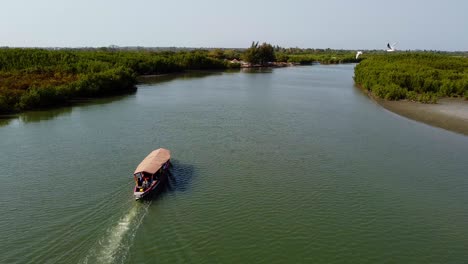 Cinematic-panoramic-shot-of-local-tourist-boat-sailing-on-River-Gambia-in-Kartong