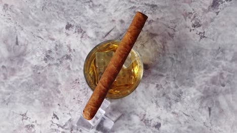 vaso de whisky con cubitos de hielo y cigarro