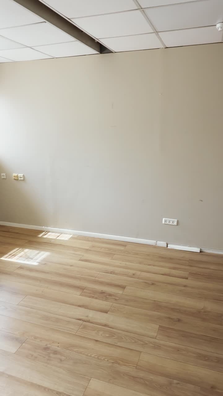 UGC style vertical phone reel of empty office floor in building with wooden parquet flooring. Vacant lot of closed bankrupt business foreclosure or new modern start up moving indoors. POV social