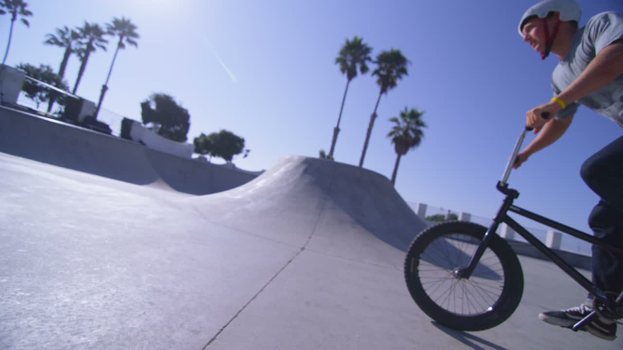la cámara sigue a un ciclista de bmx mientras salta y recorre la pared de un skatepark
