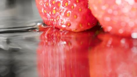 Fresas-Reflejadas-En-El-Espejo,-Las-Gotas-De-Agua-Caen-Y-Crean-Una-Ondulación,-Cámara-Lenta