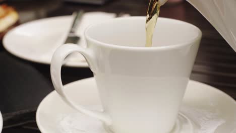 view of hot tea pouring inside white cup close-up