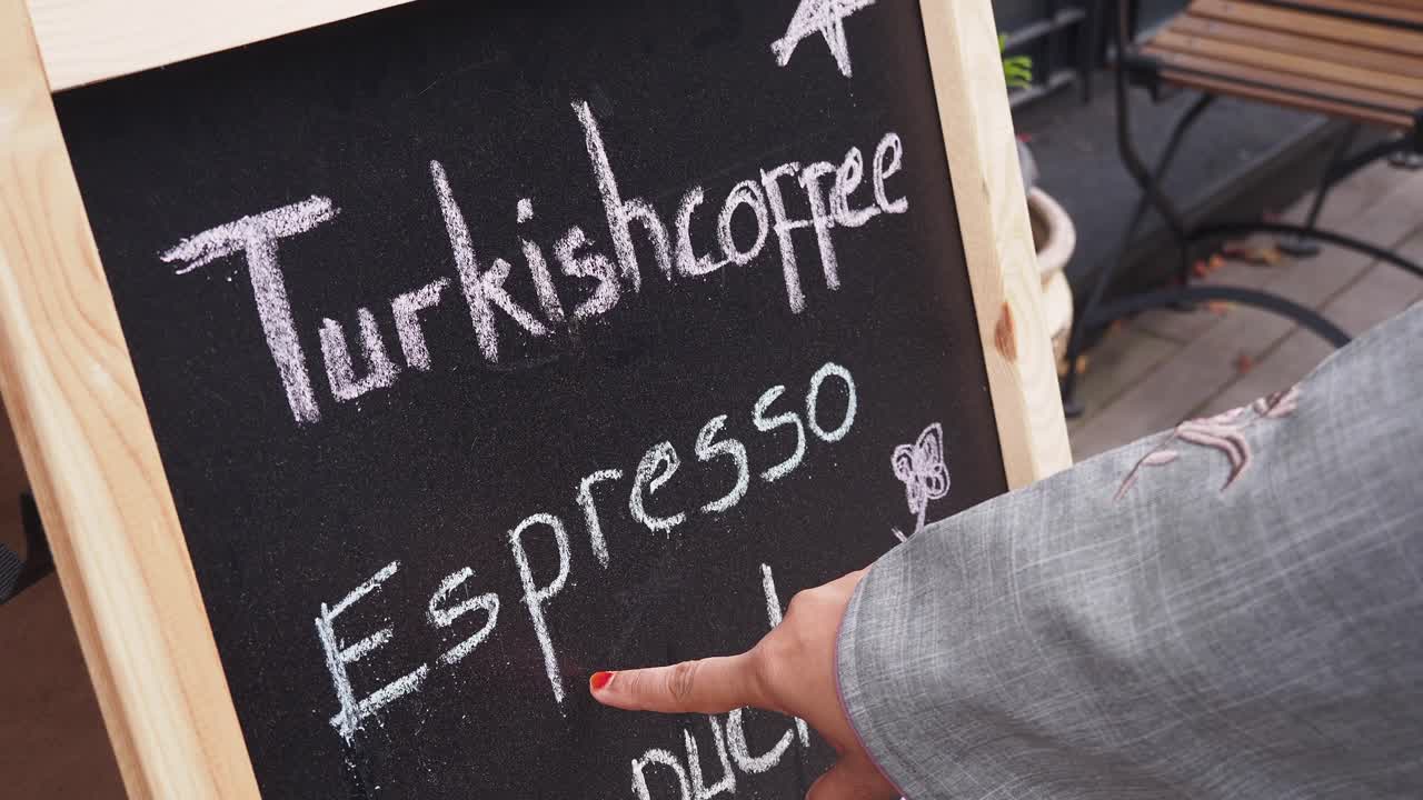 Persona che indica il caffè turco su un menù a lavagna