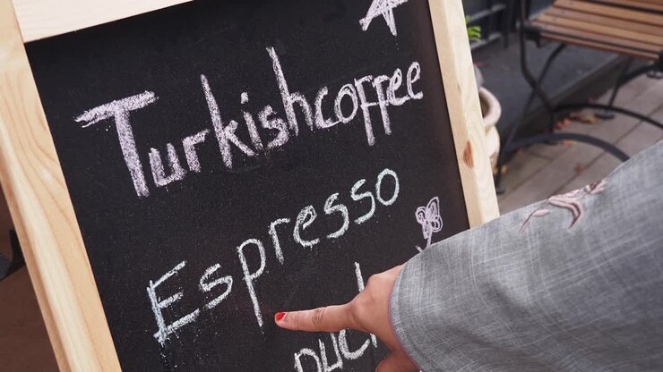 Persona che indica il caffè turco su un menù a lavagna